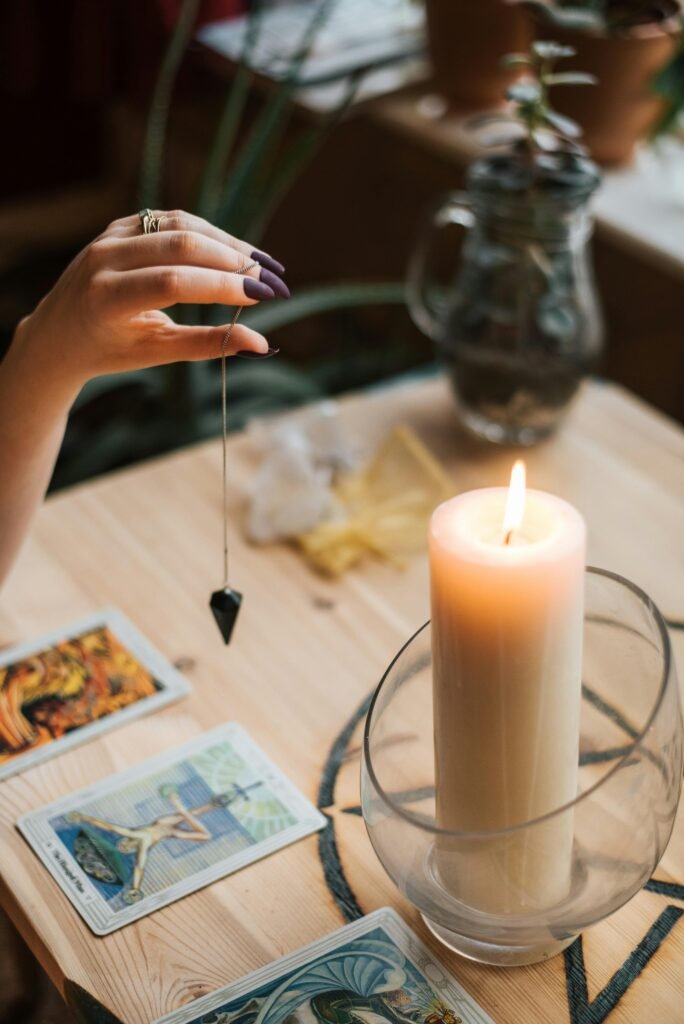 A serene tarot reading setup with a pendulum and glowing candle for divination and mindfulness.
