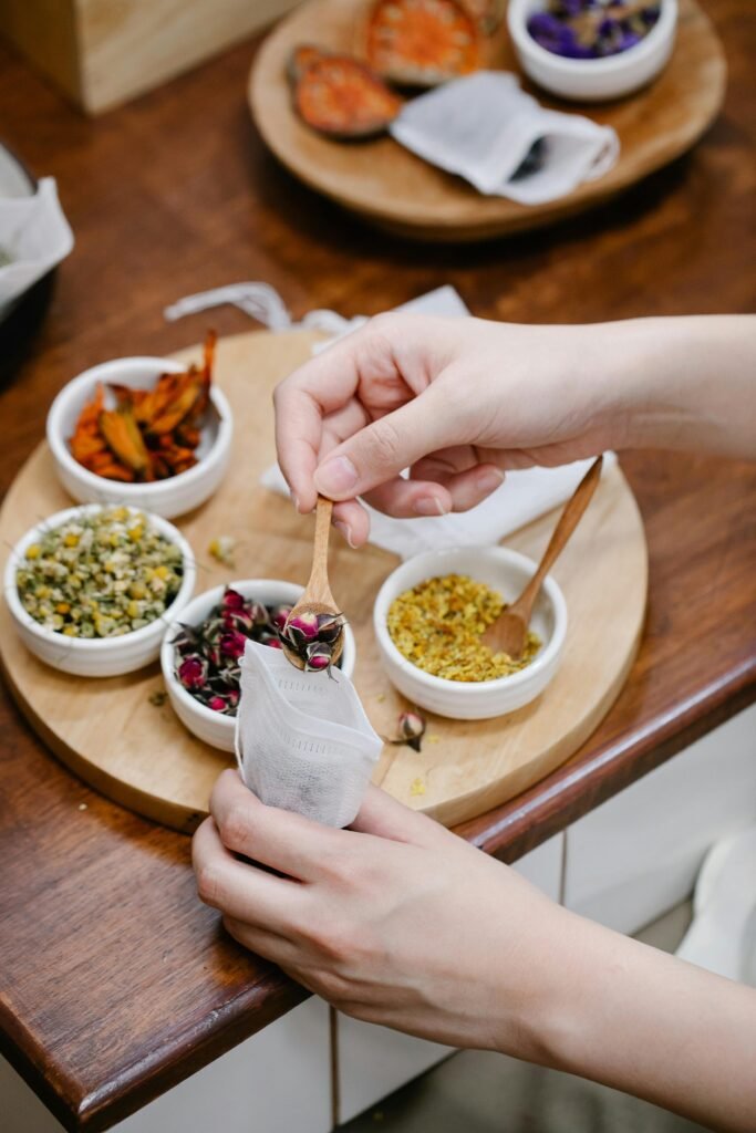 Close-up of hands crafting herbal tea blends with various spices using a wooden spoon.